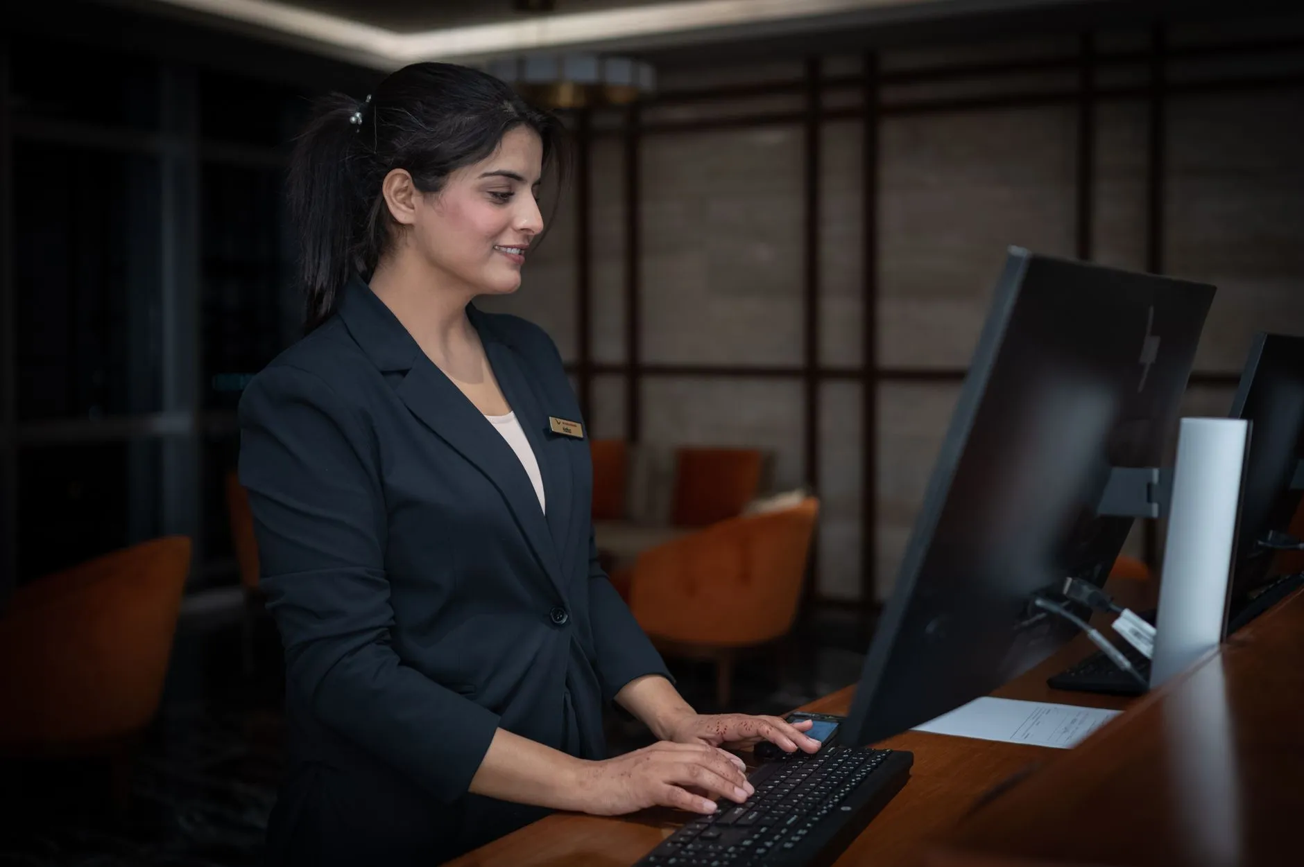 A hotel administrator at the front desk working at a computer